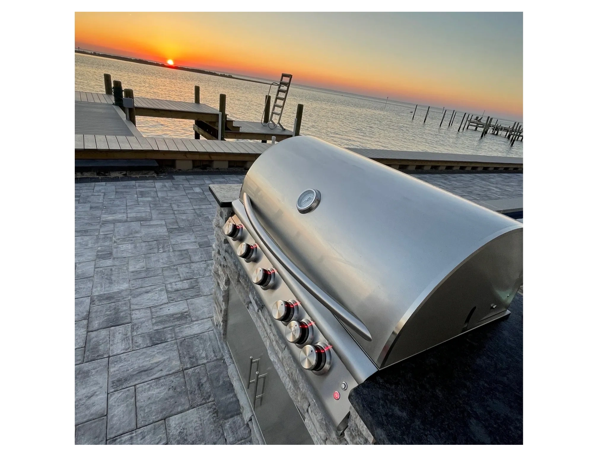 Stainless steel grill on waterfront deck at sunset